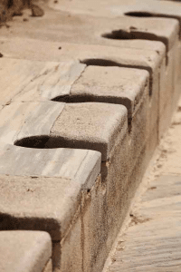 Ancient stone toilet seats illustrating early sanitation practices, relevant to the history of toilets discussed in the context of plumbing advancements.