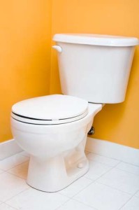 Low flow toilet against a bright yellow wall, emphasizing water-saving plumbing solutions in response to drought concerns.