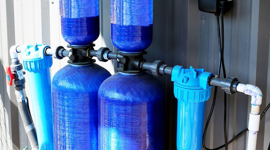 Water filtration system by Allore's Plumbing featuring two large blue tanks and piping for effective purification.