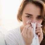 Young woman indoors holding a tissue, reflecting on plumbing service insights from Allore's Plumbing Services LLC.
