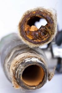 Corroded plumbing pipes showing significant buildup and deterioration, illustrating the risks of pipe corrosion and the importance of regular plumbing maintenance.