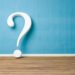 3D question mark symbol against a light blue wall and wooden floor, illustrating inquiry in plumbing maintenance topics.