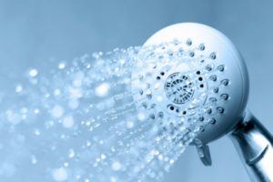 Showerhead with water flowing, emphasizing water efficiency and conservation tips for reducing water bills.