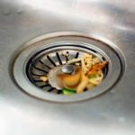 Messy kitchen sink drain filled with vegetable scraps; Allore's Plumbing Services addresses plumbing maintenance tips.