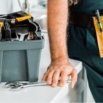 Person in work attire organizing tools in gray toolbox, representing Allore's Plumbing Services' professional approach.